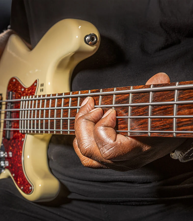 A player fretting the strings of a four-string bass.