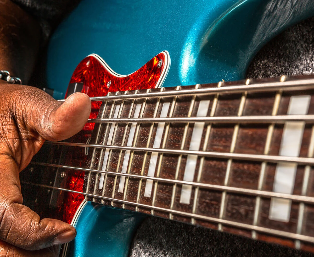 A player fretting the strings of a five-string bass.