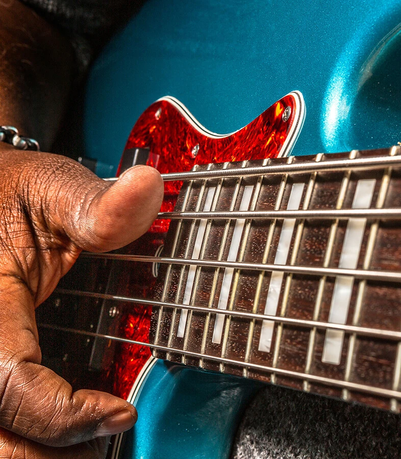 A player fretting the strings of a five-string bass.