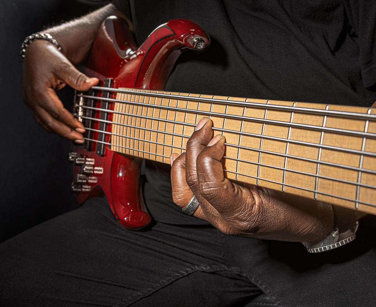  A player fretting the strings of a six-string bass.