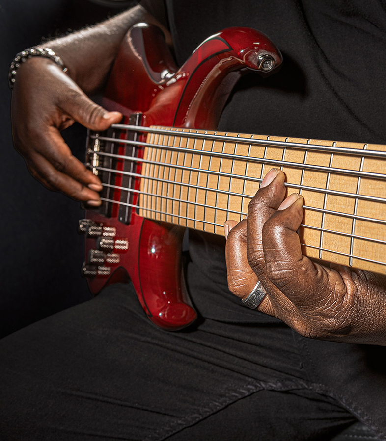  A player fretting the strings of a six-string bass.