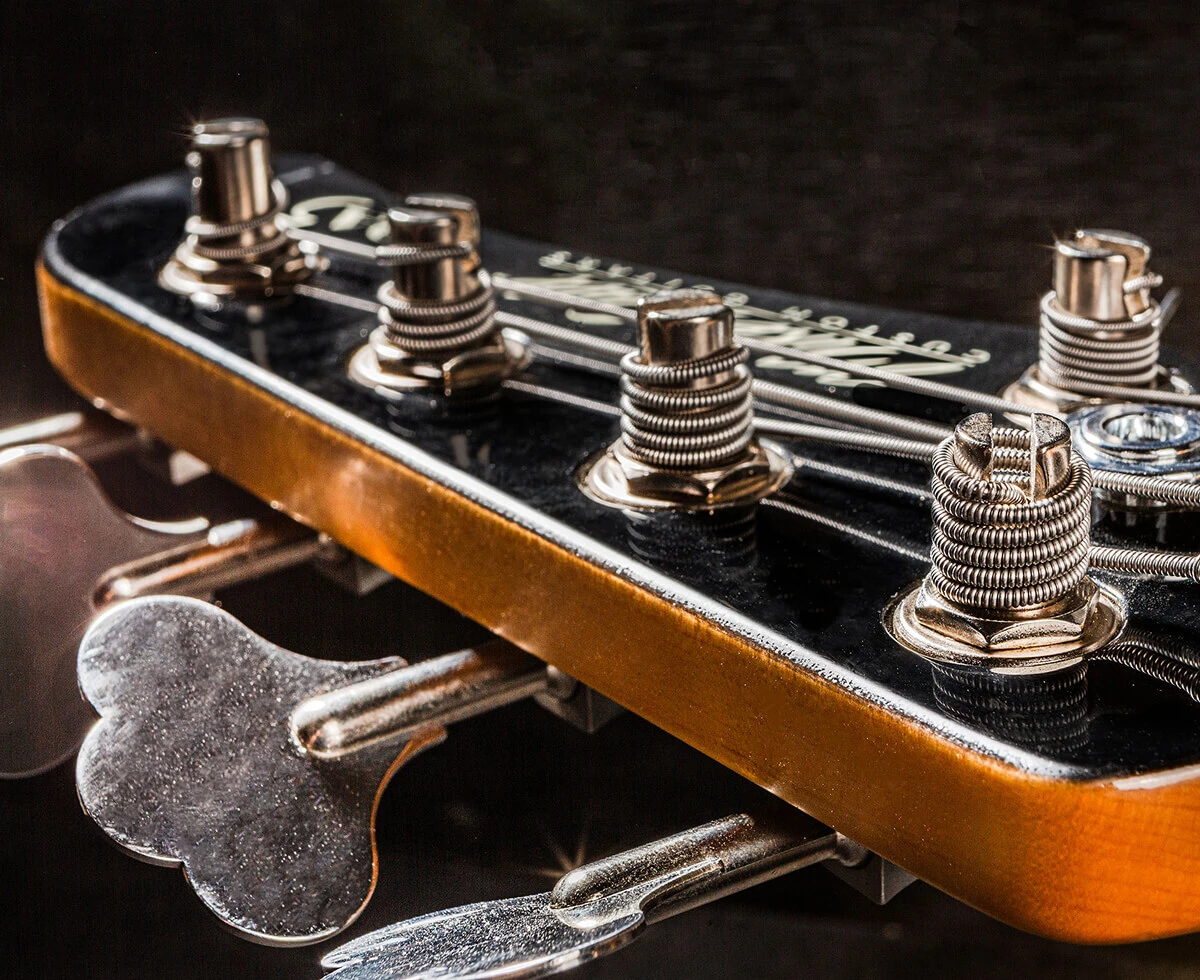 Strings wound around the tuning posts on a bass headstock.