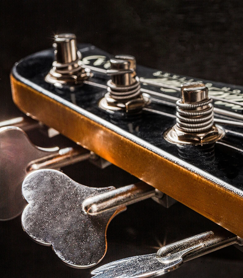 Strings wound around the tuning posts on a bass headstock.