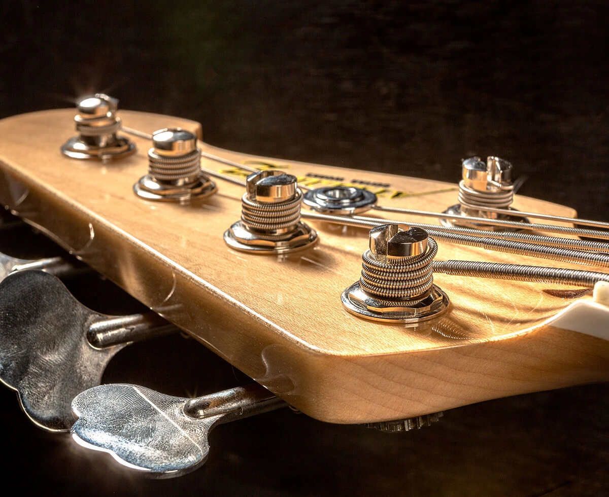 Strings wound around the tuning posts on a bass headstock.
