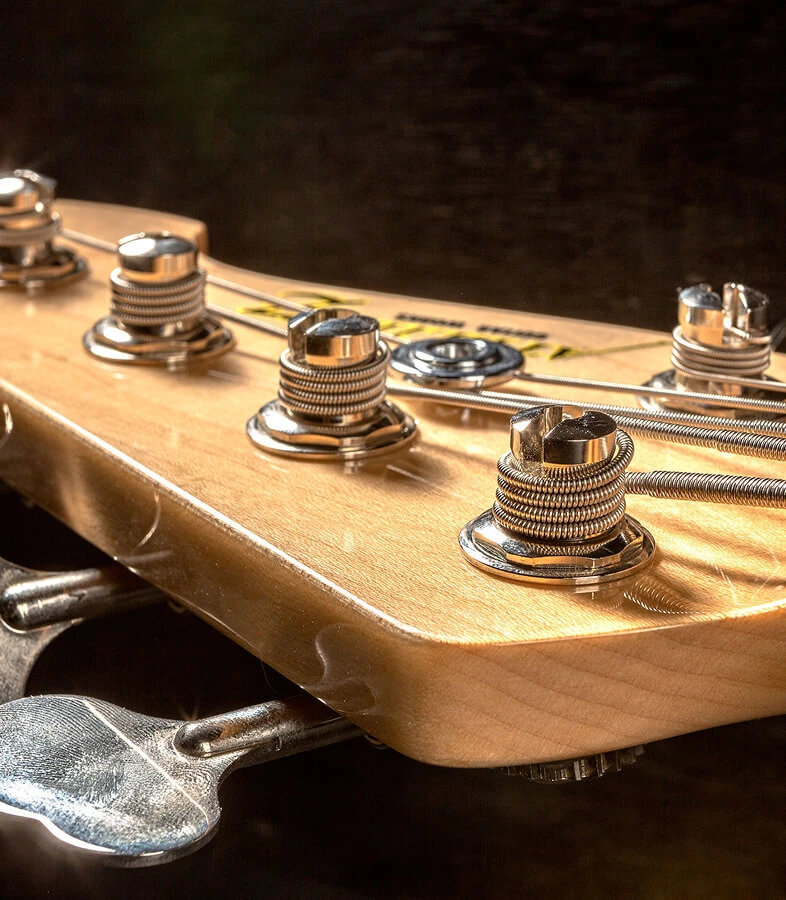 Strings wound around the tuning posts on a bass headstock.