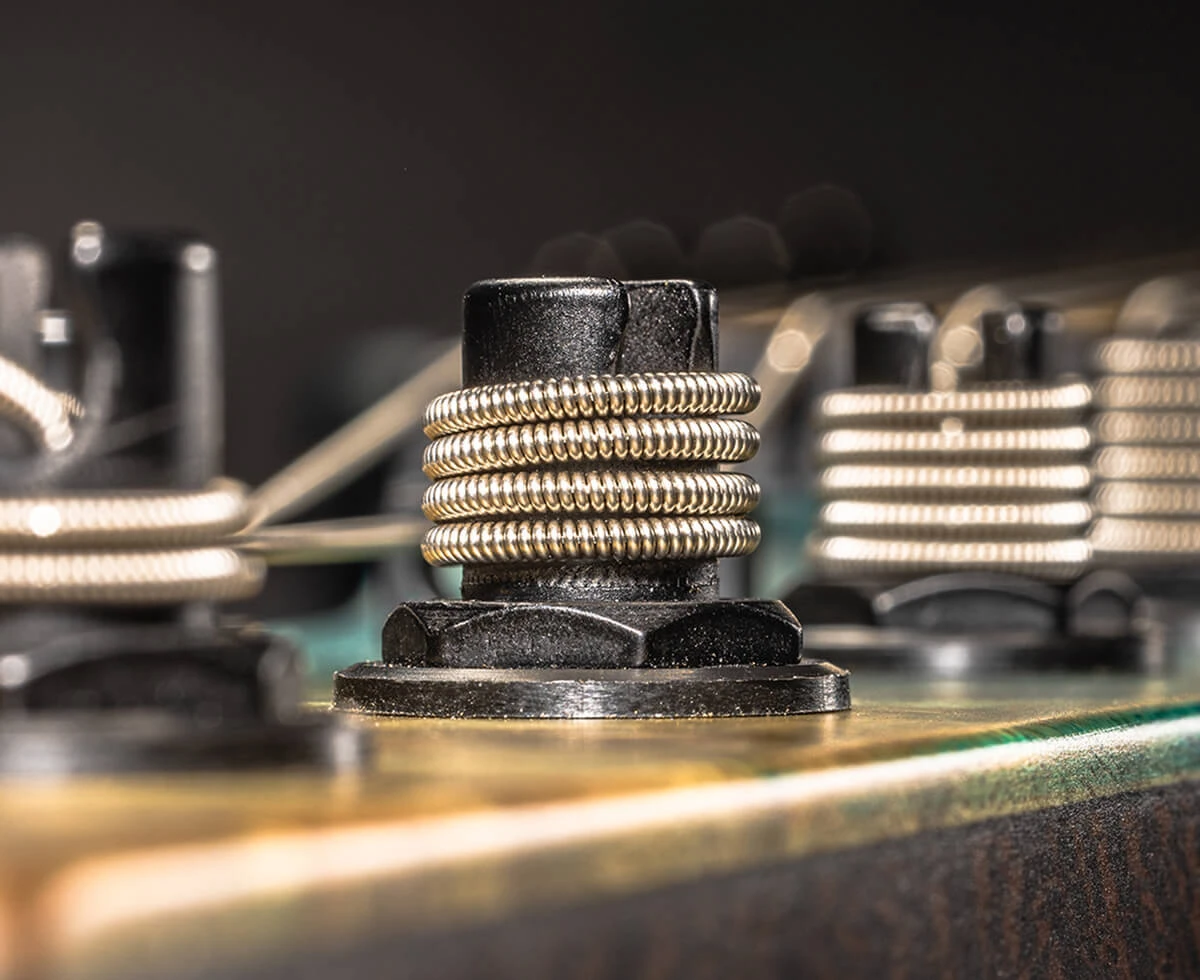 Strings wound around the tuning posts on a bass headstock.