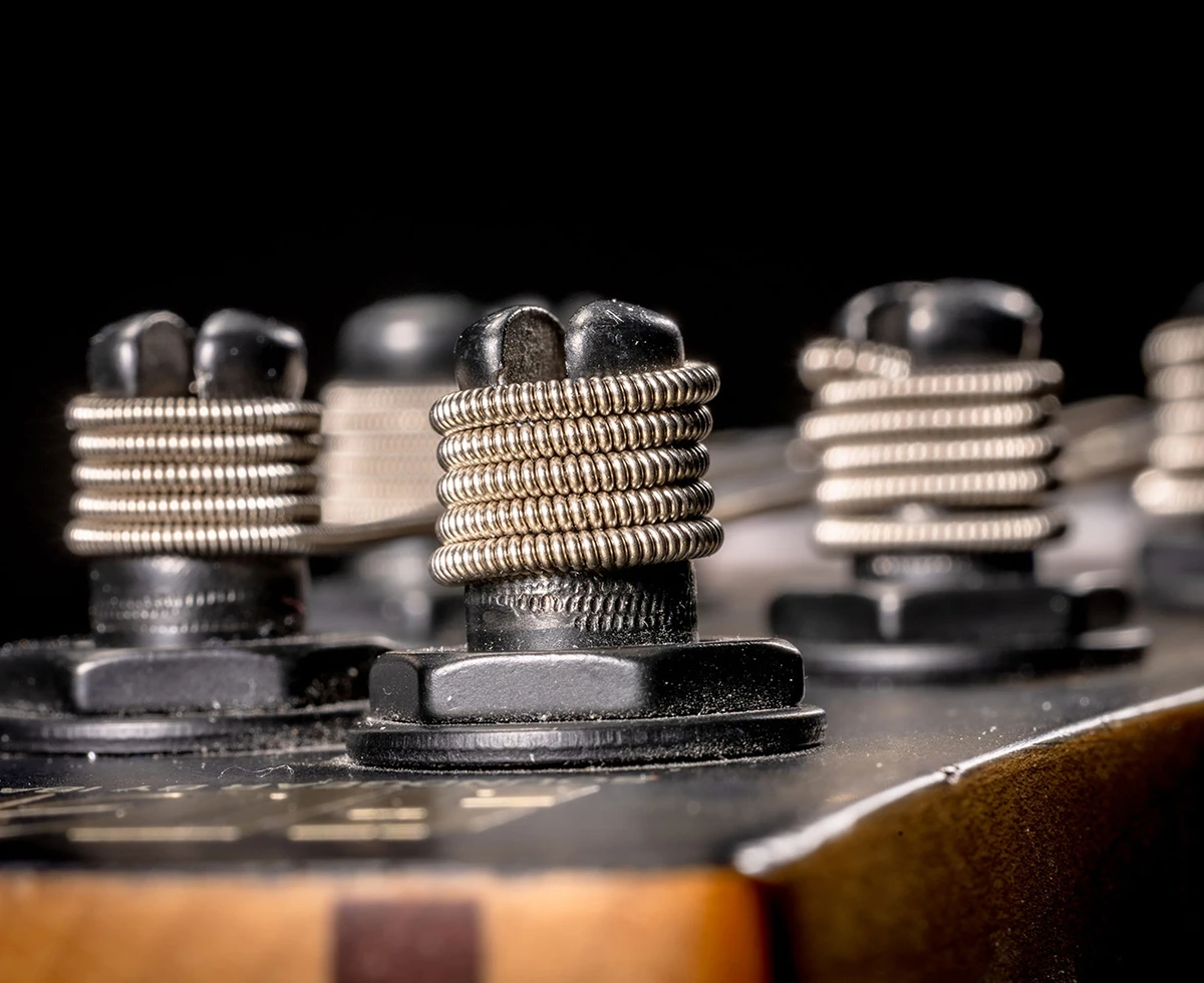 Strings wound around the tuning posts on a bass headstock.