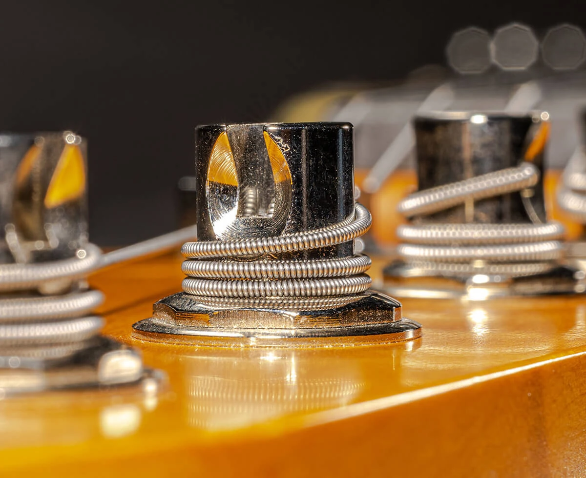 Strings wound around the tuning posts on a bass headstock.