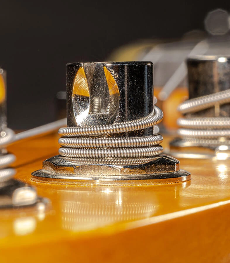 Strings wound around the tuning posts on a bass headstock.
