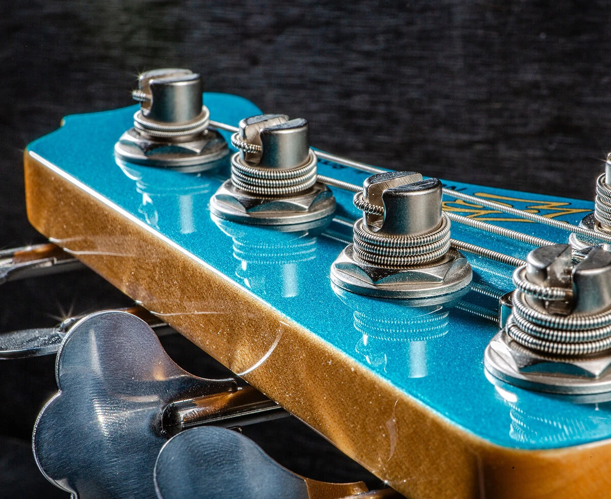 Strings wound around the tuning posts on a bass headstock.