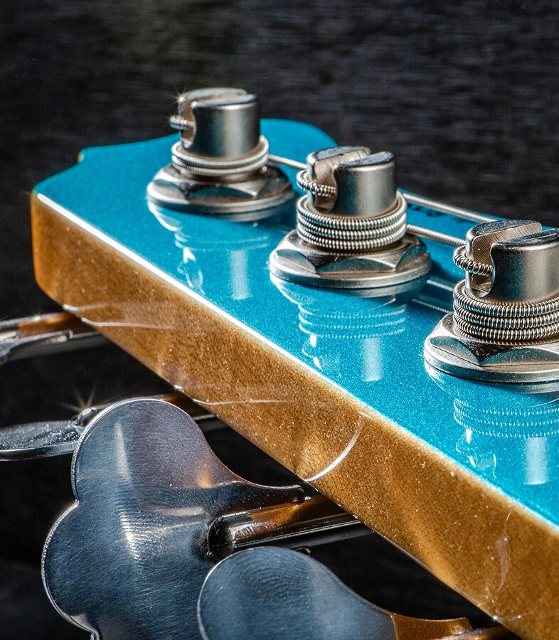 Strings wound around the tuning posts on a bass headstock.