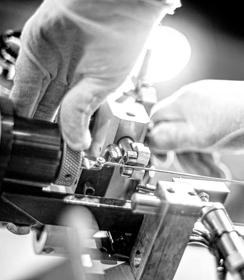 Gloved hands winding a bass string on a machine.
