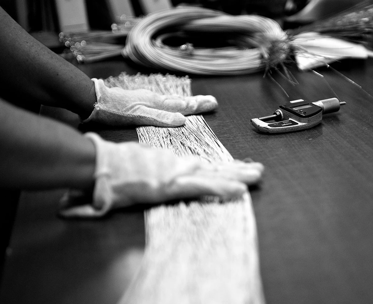 Gloved hands sorting bundles of bass string wire on a workbench.
