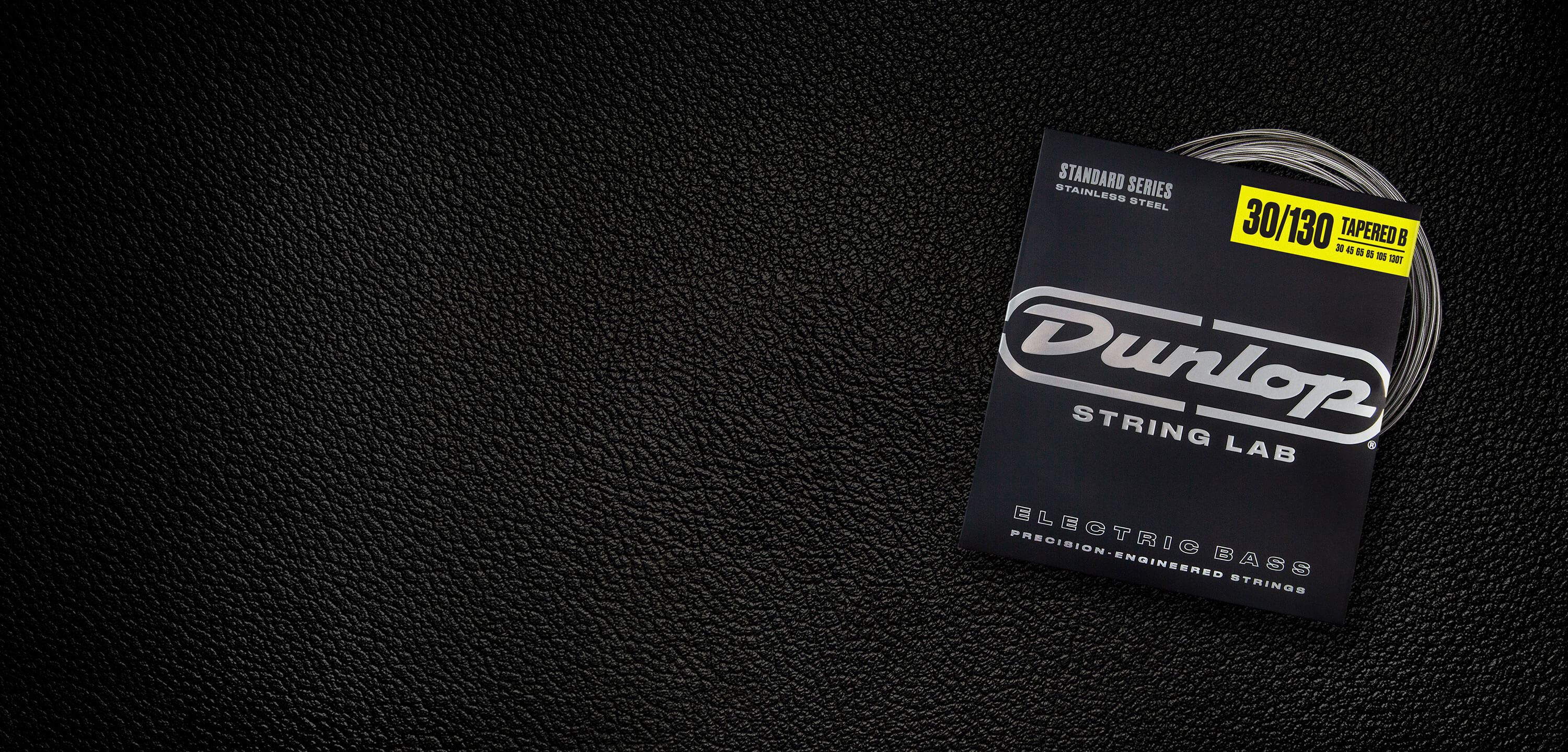 A Dunlop bass string package with the coiled strings fanned out beside it.