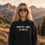 Back view of woman wearing a black “Without White Girls What Is Life” graphic T-shirt outdoors