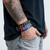 Black Confederate Flag studded bracelet featuring red, white and blue flag artwork with flames, silver-tone metal spikes and buckle closure, worn on a tattooed wrist.