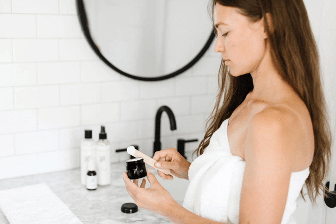 woman in a towel using a lotion in a bathroom