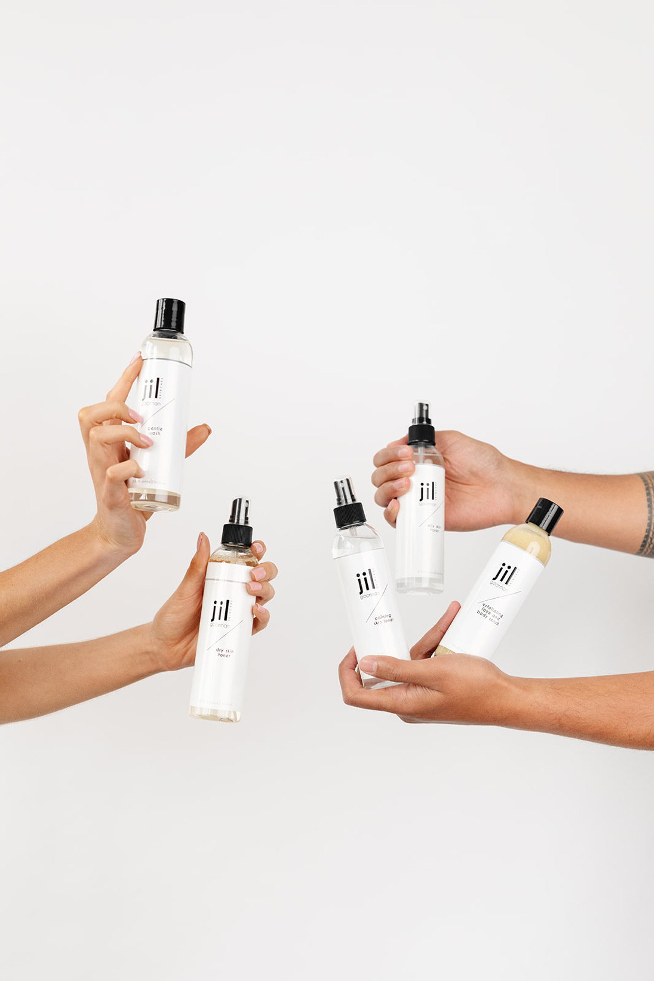 four arms holding a total of five beauty products 
