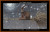 A cross-stitch pattern that depicts a whimsical scene of a brown hare perched on a broomstick against a starry night sky. The hare, with distinctively large ears and bright eyes, is seated towards the right side of the wooden broomstick, which stretches horizontally across the image. The background is a textured, dark sky sprinkled with white specks resembling stars or snowflakes. In the upper left corner, a stylized glowing moon is visible, surrounded by soft halos of light. The broomstick has twigs fanned out at one end, adding to its rustic appearance.