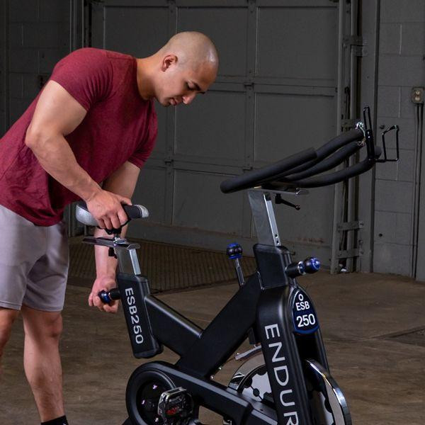 Body-Solid (ESB250) Endurance Indoor Cycle - Man Adjusting Seat Height in Gym