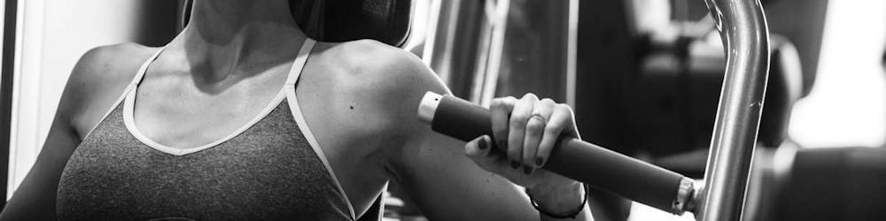 Woman Exercising on Chest Press Machine in Commercial Gym