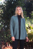 Woman's open-front possum merino cardigan in sage green, styled with a black top and dark jeans.