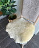 Cream colored shortwool sheepskin rug draped over a light brown wooden chair - adding natural comfort and Scandinavian charm.