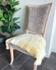 Cream colored shortwool sheepskin rug draped over a light brown wooden chair - adding natural comfort and Scandinavian charm.