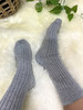 Gray ribbed alpaca wool socks on feet resting on a fluffy sheepskin rug.