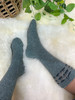 Close up of feet wearing gray knitted socks with wave trimming.