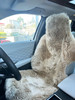 Universal sheepskin car seat cover installed on a black leather car seat in sand colour