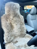 Side profile view of a universal sheepskin seat cover fitted over a car headrest side profile