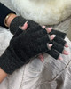 Close up of a woman's hand wearing dark gray open finger gloves made of knitted possum fur, layered with polyprop for added durability.