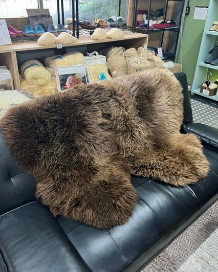 Natural black sheepskin rugs draped on a couch.