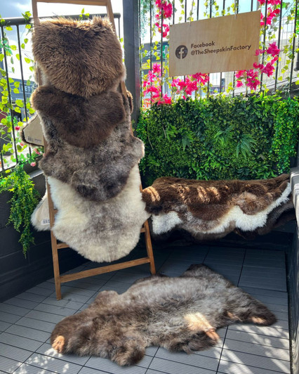 A cosy garden corner with natural black sheepskin rugs on the bench and draped on a ladder.