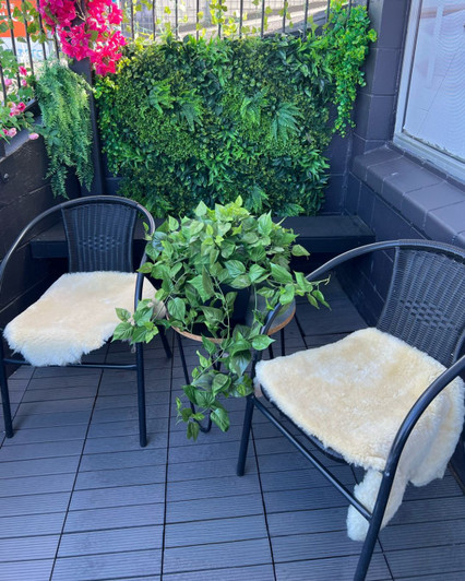 Cosy al fresco set up with light colored sheepskin rugs draped over black patio chairs.