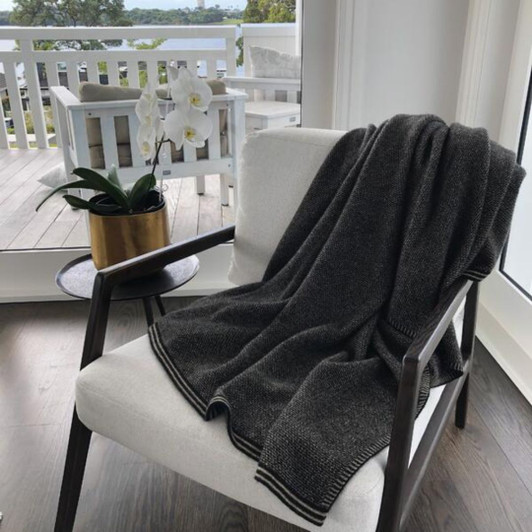 Possum Merino Deluxe Blanket draped over a chair