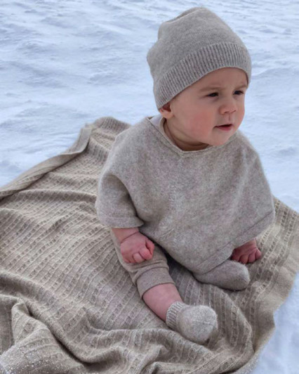 Cute baby boy wearing a Merino Silk Baby Kea Poncho