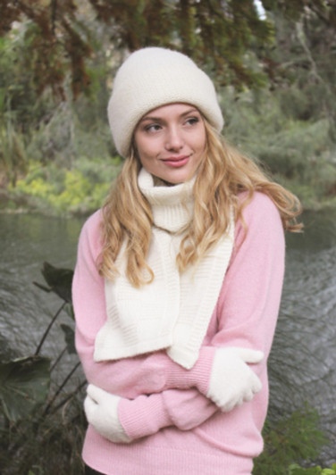 A woman wearing a white knit beanie, matching wool scarf and gloves and a rose pink sweater. A woman wearing a white knit beanie, matching wool scarf and gloves and a rose pink sweater.