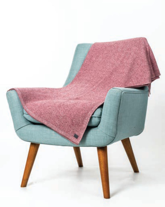 Dark pink possum merino throw draped on a mint green leather armchair.