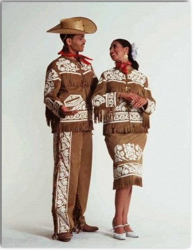 The man wears a brown suede-style outfit with white embroidery, long fringe, a cowboy hat, and a red neckerchief—reflecting northern ranching culture.

The woman wears a matching embroidered jacket and skirt with fringe, elegant heels, and her hair styled back with a decorative accessory.

The embroidery often features regional motifs inspired by ranch life and indigenous patterns.

These outfits are commonly worn for polkas, redovas, chotís, and other dances typical of Tamaulipas.