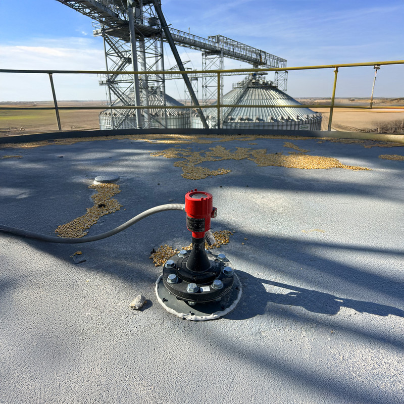BinMaster radar level sensor mounted atop a large grain storage bin used in bioenergy production