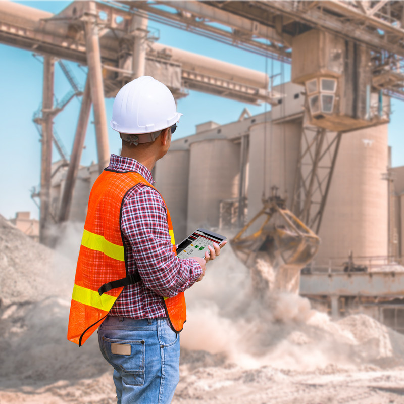 Worker views remote monitoring software while keeping a safe distance from processing