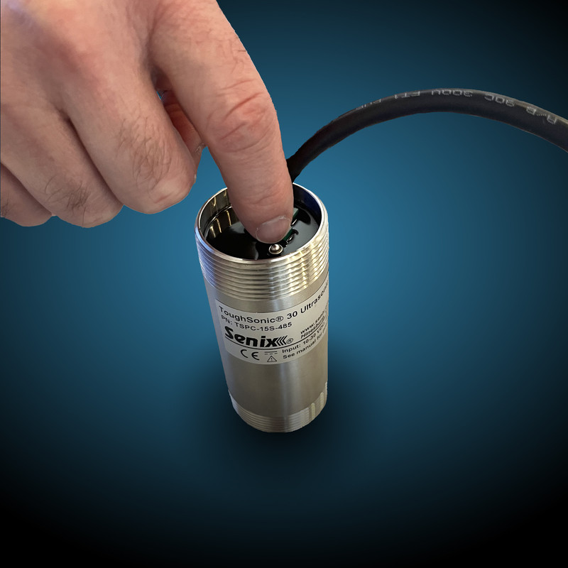 Demonstration of the location of the push-button on the back of a TS-100.30 general-purpose ultrasonic sensor