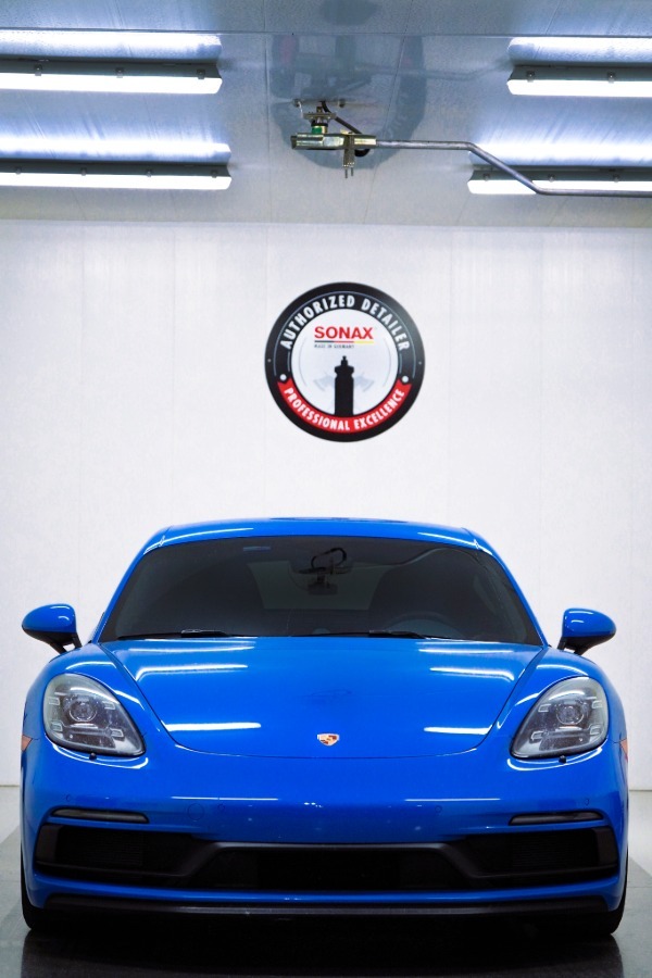 Shiny Porsche 718 in Shark Blue with dark tinted windows.