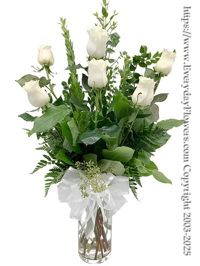 The white rose bouquet arranged in a cylinder vase with a white bow.