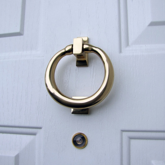 ring door knocker brass on white door