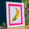 Banana print with neon pink mount in a white frame