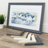 Framed artwork on a desk with samples of picture frame mouldings.