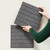 Dark grey acoustic tiles being placed on a wall.
